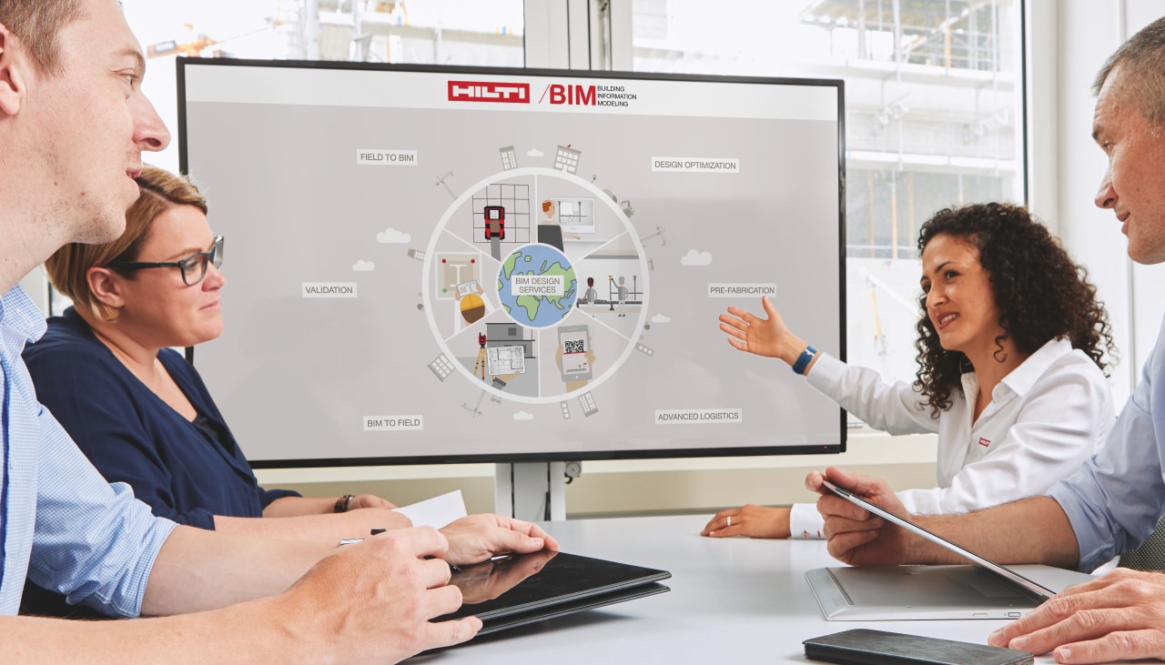Four construction professionals sitting at a table discussing E2E end-to-end workflows using BIM